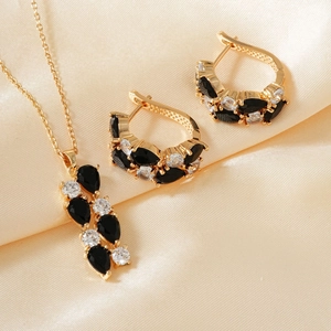 Detail von goldenem Schmuckset mit schwarzen Zirkonia auf glänzendem Satinstoff hintergrund