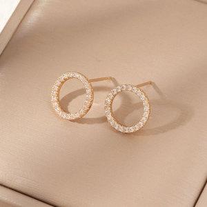 Macro shot of gold-plated circular stud earrings with pavé white zircon on silk