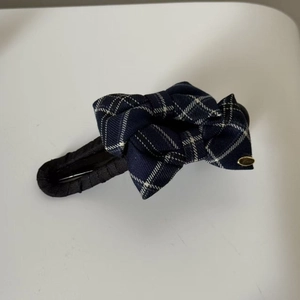 Detail of British style navy blue and white plaid bow hair clip with gold metal tag