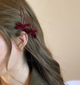 Détail de deux barrettes à nœud en velours bordeaux portées pour un style élégant et rétro