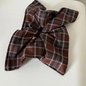 Detailed view of British style brown plaid scrunchie with bow tie in polyester fabric