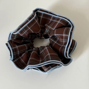 Detailed view of British style blue and brown plaid checkered fabric scrunchie with stitching