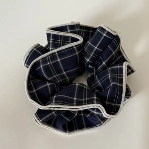 Detail of navy blue and white plaid scrunchie with classic English style stitching