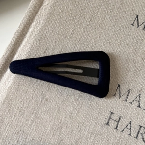 Detail of navy blue plaid fabric hair clip on a natural linen background cloth