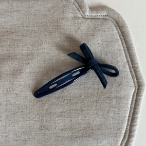 Détail d'une pince à cheveux à nœud en velours bleu marine avec base en métal poli brillant