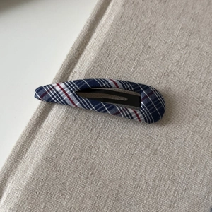 Detailed close-up of navy blue and red plaid fabric texture on a teardrop BB hair clip