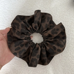 Detail of a large leopard print hair scrunchie made of soft fabric texture
