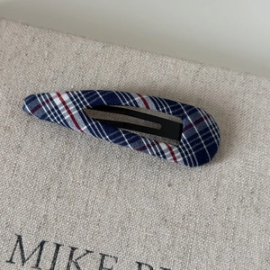 Detail of French vintage navy and red plaid fabric hairpin with a matte black metal clip