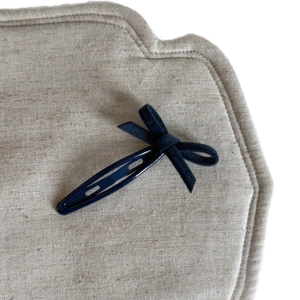 Pince à cheveux à nœud en velours bleu marine sur fond en lin beige naturel