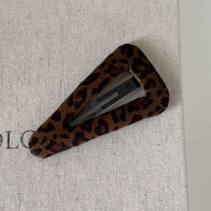 Dettaglio della trama in peluche leopardato e della clip in metallo nero della molletta BB