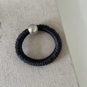 Détail d'un chouchou noir élastique avec texture soie et perle métallique argentée