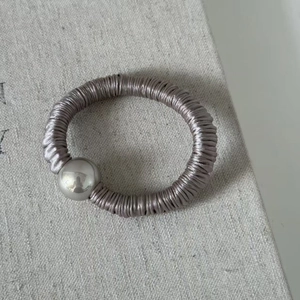 Gros plan d'un chouchou en satin violet clair avec une perle métallique argentée polie