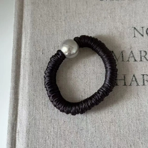 Détail d'un chouchou en soie noire avec perle métallique argentée sur texture lin