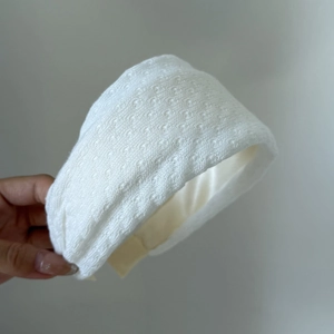 Detail of a thick white padded headband with delicate embroidered polka dot texture