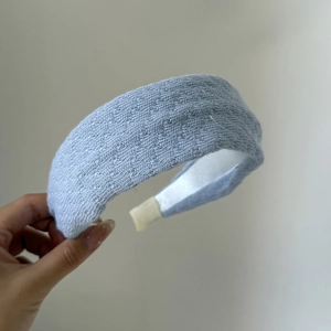 Close-up of light blue knitted headband showing soft texture and thick padded design
