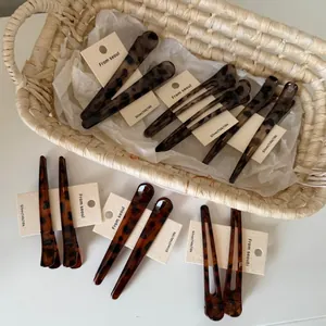 Detailed view of glossy tortoise shell hair clips displayed on a white branded card