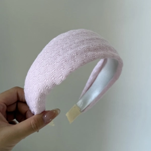Detail of pink knitted headband with delicate lace pattern and non-slip white lining