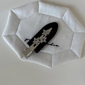 Close-up of black acetate hair clip featuring three sparkling silver diamond stars