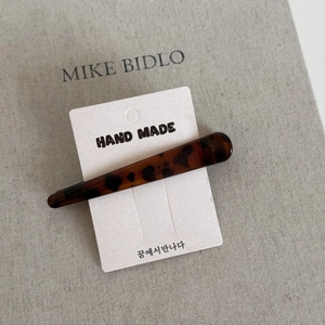 Detailed macro view of a tortoiseshell leopard print hair clip on a handmade card
