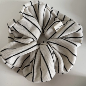 Détail d'un chouchou en maille rayée beige avec étiquette tissée noire Hand Made
