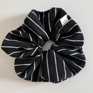 Détail d'un chouchou en tricot rayé avec une étiquette textile Hand Made blanche