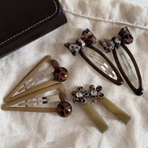 Vintage leopard print hair clip set with floral and bow designs on white canvas