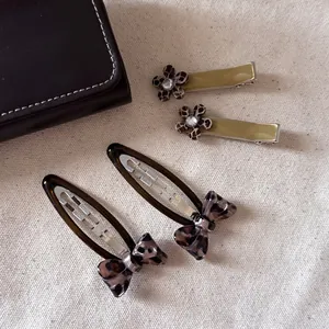Set of leopard print hair clips with flowers and bows on a vintage canvas background