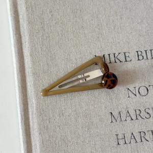 Detail of a geometric triangle hair clip with leopard print bead and handmade engraving