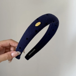 Détail du serre-tête rembourré en laine bleu marine avec cœurs et breloque Love dorée