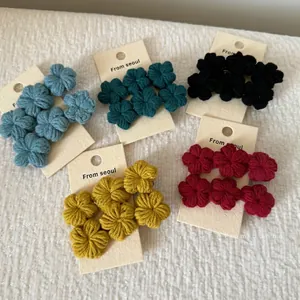 Handmade gradient crochet flower hair clips in five colors on a soft white plush background