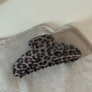 Detail of grey leopard print hair claw clip showing glossy finish and acrylic texture
