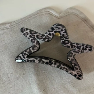 Detailed view of star-shaped grey leopard print hair claw with strong gold spring
