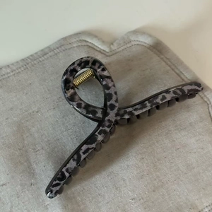 Close-up of a large grey leopard print hair claw clip with golden metal spring detail