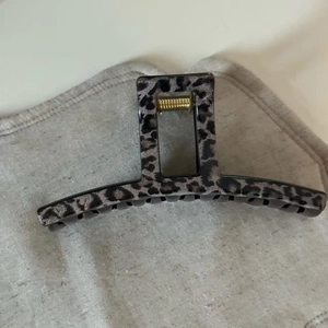 Top view of large grey leopard hair claw clip with golden metal spring and square handle