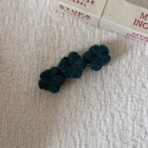 Detailed close-up of dark green handmade crochet flower hair clip with metallic back pins