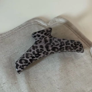 Detail of grey leopard print hair claw clip showing acrylic texture and sturdy spring