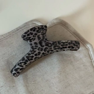 Detailed close-up of a large leopard print hair claw clip in elegant grey and black shades