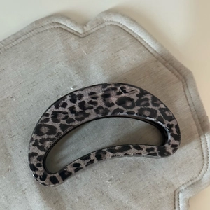 Detail view of large French grey leopard print hair claw clip on linen background