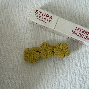 Detail of three mustard yellow hand-woven crochet flowers on a minimalist hair clip