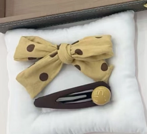 Detail of yellow polka dot fabric bow scrunchie and brown matte hair clip set