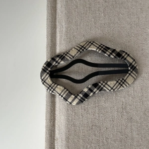 American college style black and white plaid fabric wavy hair clip on beige background