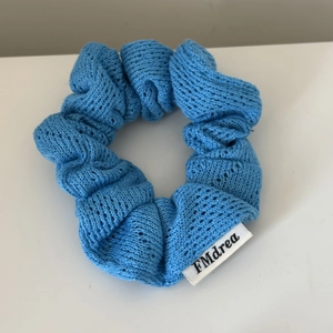 Sky blue knitted hair scrunchie with soft hollow texture and branded label for ponytail