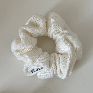 Detailed macro view of the cream-colored knit scrunchie with hollow crochet texture