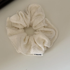 Detailed macro view of white hollow knit hair scrunchie with subtle brand fabric label