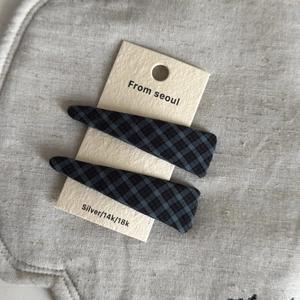 Detail view of two gray plaid fabric BB hair clips on a simple paper card holder