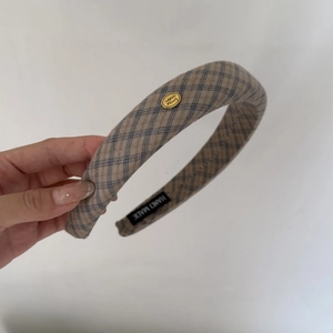 Detail of plaid fabric headband with gold SMILE HAPPY button and handmade label