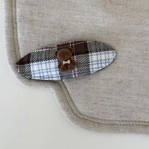Détail macro d'une barrette ovale à carreaux avec un petit ours en peluche 3D floqué