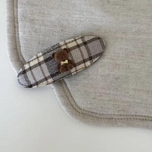 Gros plan sur une pince à cheveux à carreaux marron avec un petit ours floqué mignon