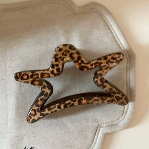 Detailed view of leopard print star-shaped hair claw clip with golden metal spring