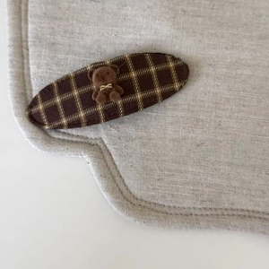 Détail d'une pince à cheveux à carreaux marron avec un joli petit ours en peluche en 3D
